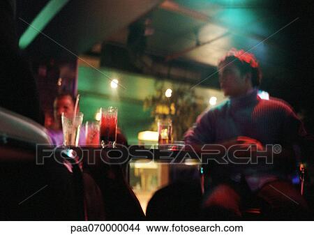 Young man sitting in bar, second person in background, low angle view View Large Photo Image Picture - Young man sitting in bar, second person in background, low angle view. Fotosearch