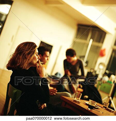 Young people sitting indoors, one smoking View Large Photo Image Stock Image - Young people sitting indoors, one smoking. Fotosearch