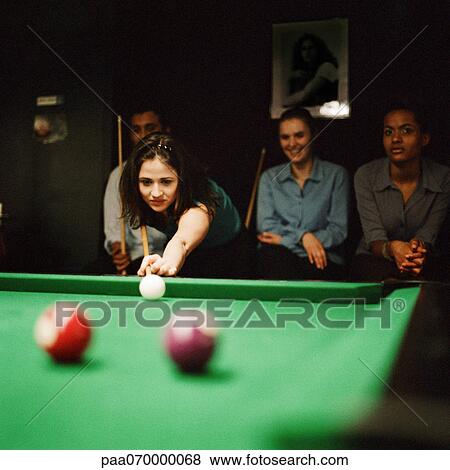 Stock Photo - Young woman shooting pool, young people sitting in background. Fotosearch