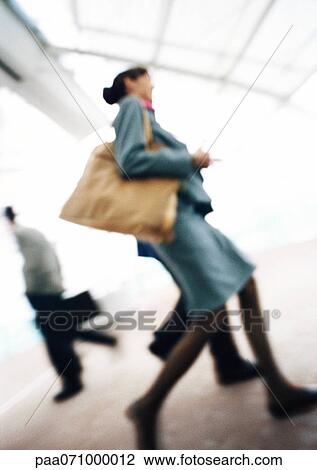 Stock Image - Business people walking, low angle view, blurred.. Fotosearch