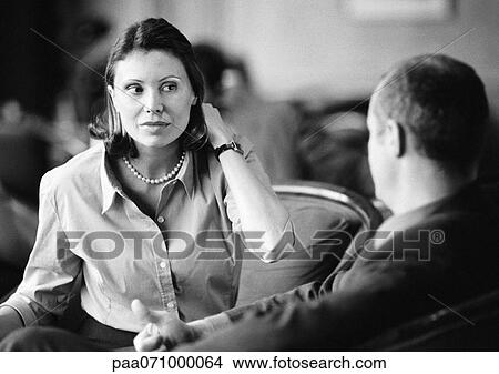 Picture - Businessman and businesswoman sitting together, talking, b&w.. Fotosearch