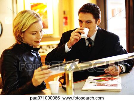 Stock Photograph - Businessman and businesswoman sitting together at counter, looking at ticket.. Fotosearch