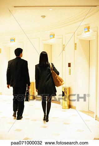 Businessman and businesswoman walking toward elevators, rear view. View Large Photo Image Stock Image - Businessman and businesswoman walking toward elevators, rear view.. Fotosearch