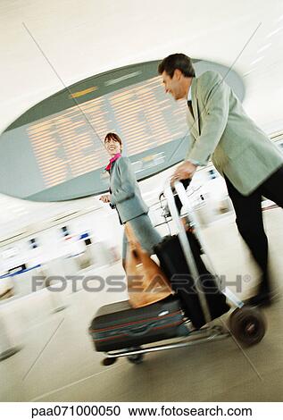 Businessman and businesswoman walking through airport terminal, blurred. View Large Photo Image Stock Image - Businessman and businesswoman walking through airport terminal, blurred.. Fotosearch