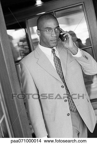 Picture - Businessman using cell phone in doorway, b&w.. Fotosearch