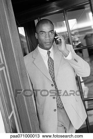 Businessman using cell phone in doorway, b&w. View Large Photo Image Stock Image - Businessman using cell phone in doorway, b&w.. Fotosearch