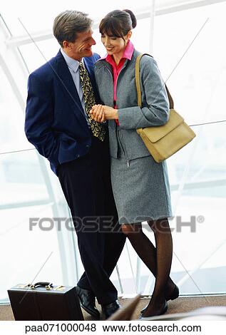 Businessman with briefcase on floor and businesswoman standing close together in front of window. View Large Photo Image Stock Photo - Businessman with briefcase on floor and businesswoman standing close together in front of window.. Fotosearch