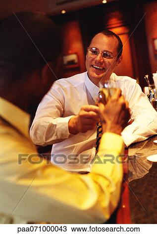 Businessmen raising glasses at bar. View Large Photo Image Stock Image - Businessmen raising glasses at bar.. Fotosearch