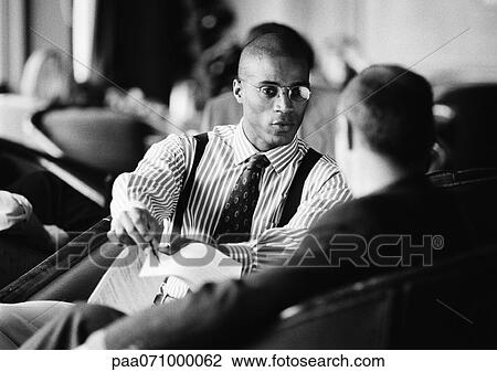 Businessmen sitting, discussing document, b&w. View Large Photo Image Stock Image - Businessmen sitting, discussing document, b&w.. Fotosearch