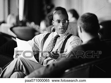 Businessmen sitting, discussing document, b&w. View Large Photo Image Stock Photography - Businessmen sitting, discussing document, b&w.. Fotosearch