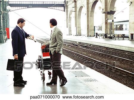 Businessmen standing on train platform, one looking at watch. View Large Photo Image Stock Image - Businessmen standing on train platform, one looking at watch.. Fotosearch