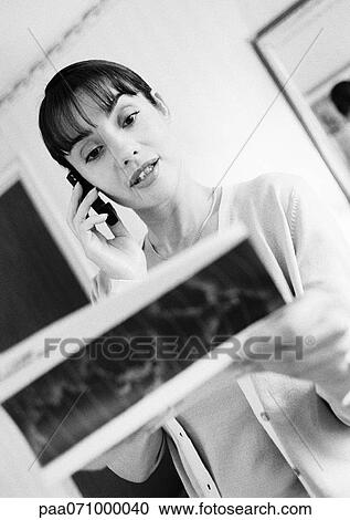 Businesswoman looking down at travel ticket, talking on cell phone, b&w. View Large Photo Image Stock Image - Businesswoman looking down at travel ticket, talking on cell phone, b&w.. Fotosearch