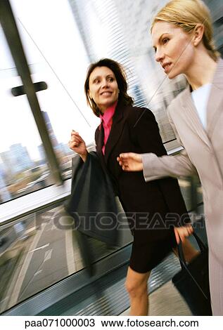 Businesswomen walking together in elevated passageway, blurred. View Large Photo Image Stock Image - Businesswomen walking together in elevated passageway, blurred.. Fotosearch
