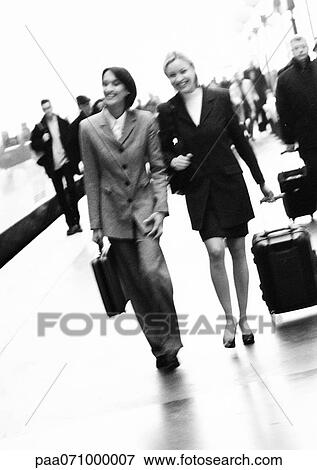 Stock Photo - Businesswomen walking together on platform, blurred, b&w.. Fotosearch
