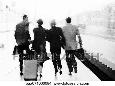 Picture - Group of business people hurrying on train platform, rear view, blurred, b&w.. Fotosearch