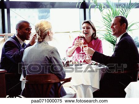 Group of business people sitting at table together, smiling and raising glasses. View Large Photo Image Stock Photography - Group of business people sitting at table together, smiling and raising glasses.. Fotosearch