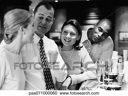Stock Image - Group of business people socializing at bar, b&w.. Fotosearch
