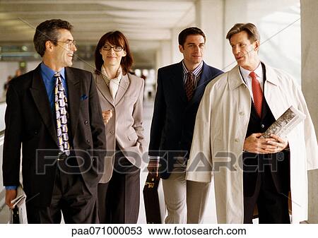 Stock Image - Group of business people walking together indoors, front view. Fotosearch
