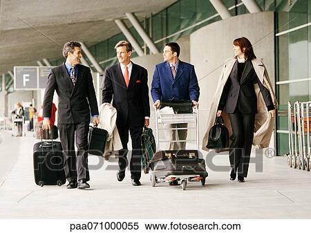 Stock Photography - Group of business people walking with luggage outside airport terminal. Fotosearch