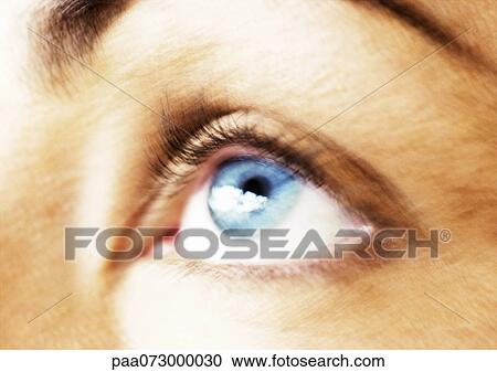 Stock Image - Woman's blue eye looking up, blurred close up.. Fotosearch