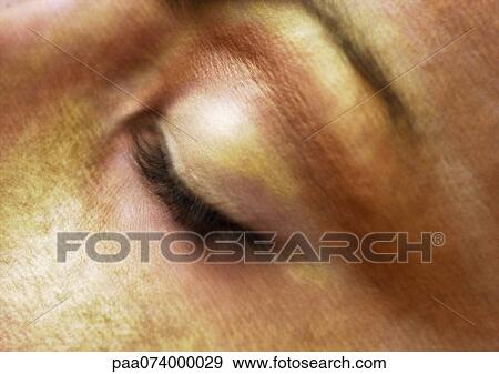 Stock Photo - Woman's closed eye, gold make-up on face, close-up, blurry.. Fotosearch