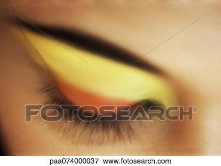 Stock Photo - Woman's closed eye with yellow and orange eye shadow, close-up. Fotosearch