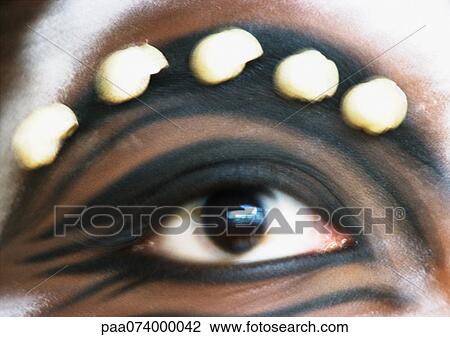 Stock Image - Woman's eye with paint and adornments, extreme close-up, blurred. Fotosearch