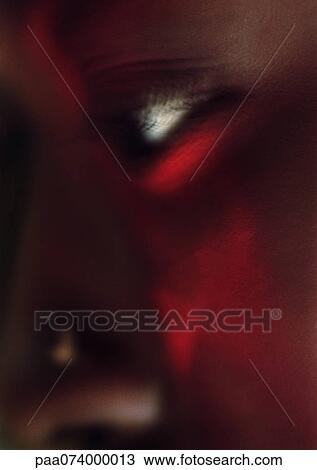 Stock Image - Woman's eye with red make-up on face, close-up. Fotosearch