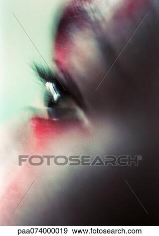 Stock Photo - Woman's eye with red make-up on face, close-up, blurred. Fotosearch