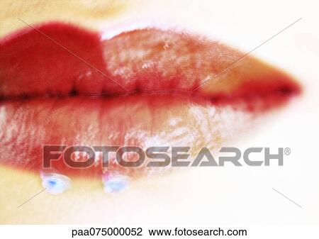 Stock Image - Woman wearing red lipstick, close up of mouth with jewel adornments, blurred.. Fotosearch