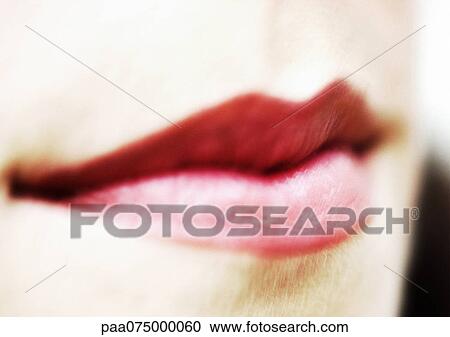 Stock Image - Woman wearing red lipstick, close up of mouth, blurred.. Fotosearch