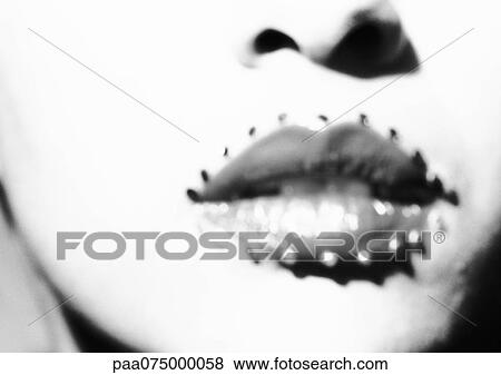 Stock Photo - Woman's mouth with jewel adornments, close up of lower face, black and white, blurred. . Fotosearch