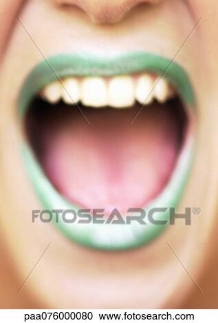 Stock Image - Close up of woman's mouth open and smiling with green lipstick, blurred. Fotosearch