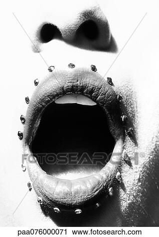 Stock Image - Close up of woman's mouth open with adornments, b&w. Fotosearch