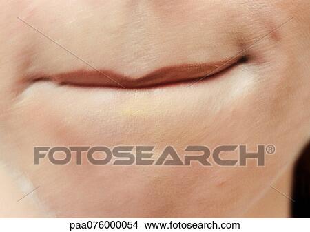 Picture - Close up of woman's mouth with bottom lip tucked in.. Fotosearch