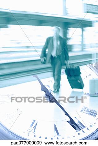 Stock Photo - Businessman with luggage walking on clock, montage. Fotosearch