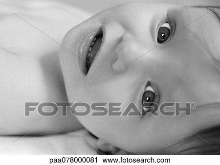 Stock Image - Baby lying down, looking at camera, B&W.. Fotosearch