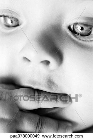 Stock Photo - Baby with hand to mouth, close-up, B&W.. Fotosearch