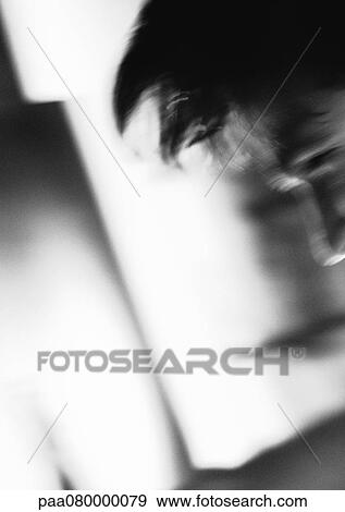 Stock Photo - Part of man's face and hair, ambiguous shapes in background, blurred, black and white.. Fotosearch