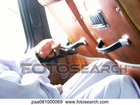 Stock Photo - Close up of hands holding prayer beads. Fotosearch
