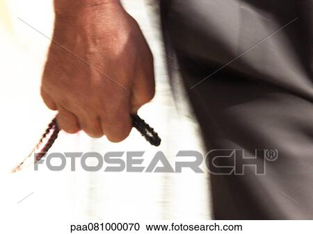 Stock Image - Close up of man's hand holding prayer beads. Fotosearch
