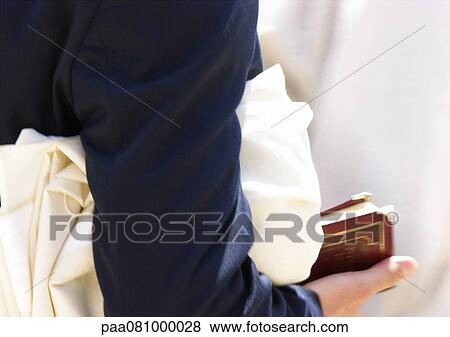 Stock Photo - Israel, Jerusalem, man holding cloth and book, close-up. Fotosearch