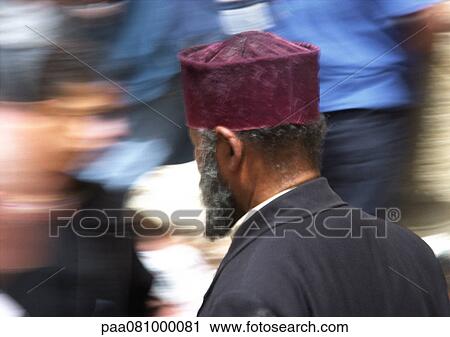 Stock Image - Israel, Jerusalem, Muslim man, rear view, blurred motion of people passing in background. Fotosearch