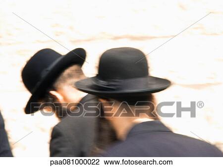 Stock Image - Israel, Jerusalem, Orthodox Jewish men praying at Wailing Wall, rear view, blurred. Fotosearch