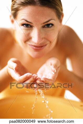 Woman cupping water in hands, smiling at camera, front view View Large Photo Image Stock Photo - Woman cupping water in hands, smiling at camera, front view. Fotosearch