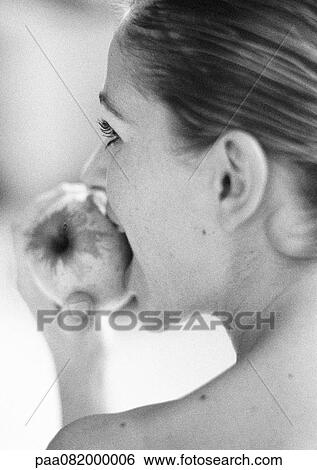 Stock Photograph - Woman eating an apple, rear view, close-up. Fotosearch