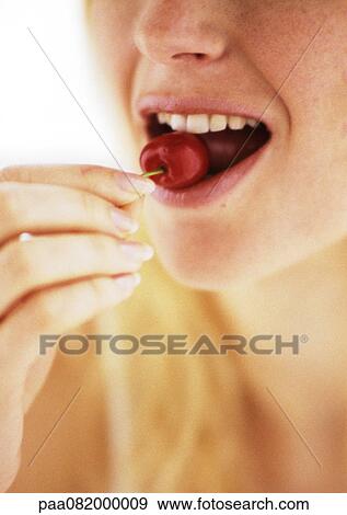 Stock Photo - Woman eating cherry, close up.. Fotosearch