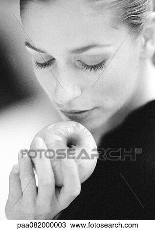 Stock Image - Woman holding apple, looking down, close-up, B&W.. Fotosearch