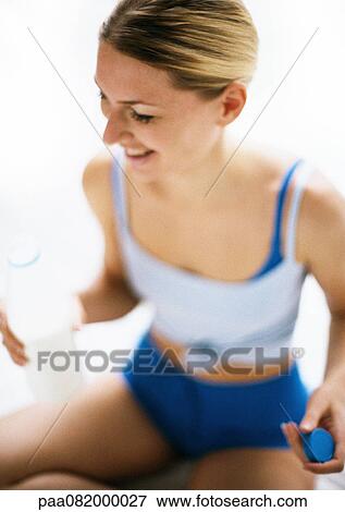 Woman in workout clothes holding bottle, smiling, high angle view View Large Photo Image Stock Photo - Woman in workout clothes holding bottle, smiling, high angle view. Fotosearch