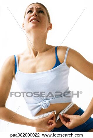 Woman looking up, measuring waist with measuring tape, low angle view View Large Photo Image Stock Image - Woman looking up, measuring waist with measuring tape, low angle view. Fotosearch